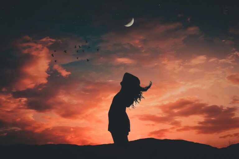 A silhouetted person under a crescent moon at twilight, evoking tranquil and peaceful vibes.